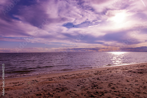 Soft pastel sunset over a calm ocean, with gentle waves and a serene beach under a peaceful sky photo