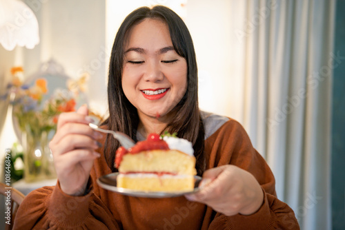 Beautiful Asian woman eating tasty cake. Teen girl eating the cake.