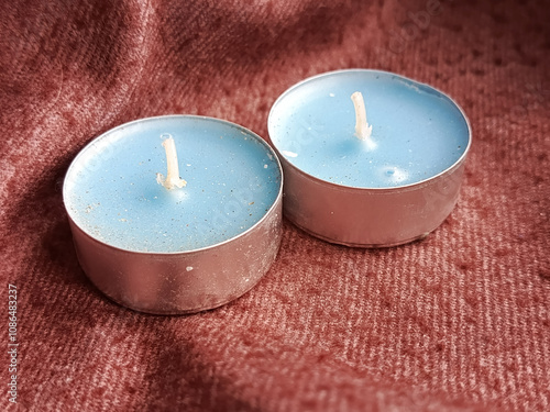 Blue scented candles in a metal stand on a brown, woolen blanket. The background for the advertisement, the place for the text. Winter and autumn comfort at home. photo