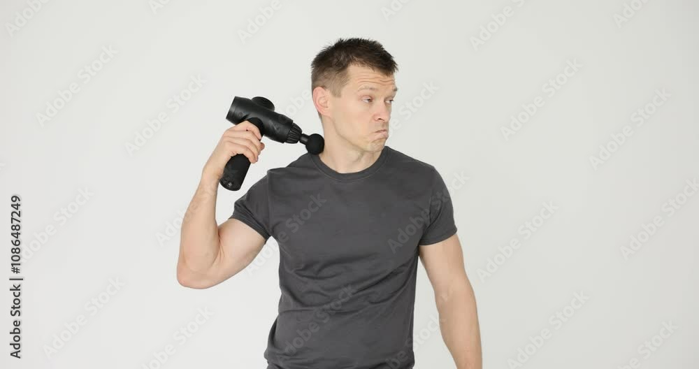 Man holding black massage gun, white studio background Man holding black massage gun, white studio background