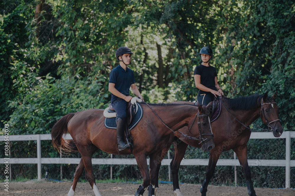 Two young riders enjoy horseback riding in a scenic, green outdoor environment, showcasing equestrian skills and companionship amidst nature. Two young riders enjoy horseback riding in a scenic, green outdoor environment, showcasing equestrian skills and companionship amidst nature.