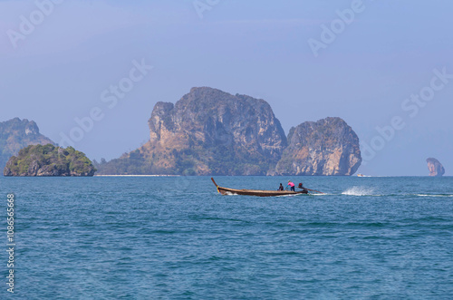 Wooden long tail boat sailing in turquoise sea between koh tup island and Koh kai island under blue sky in summer day Krabi, Thaiand.  photo