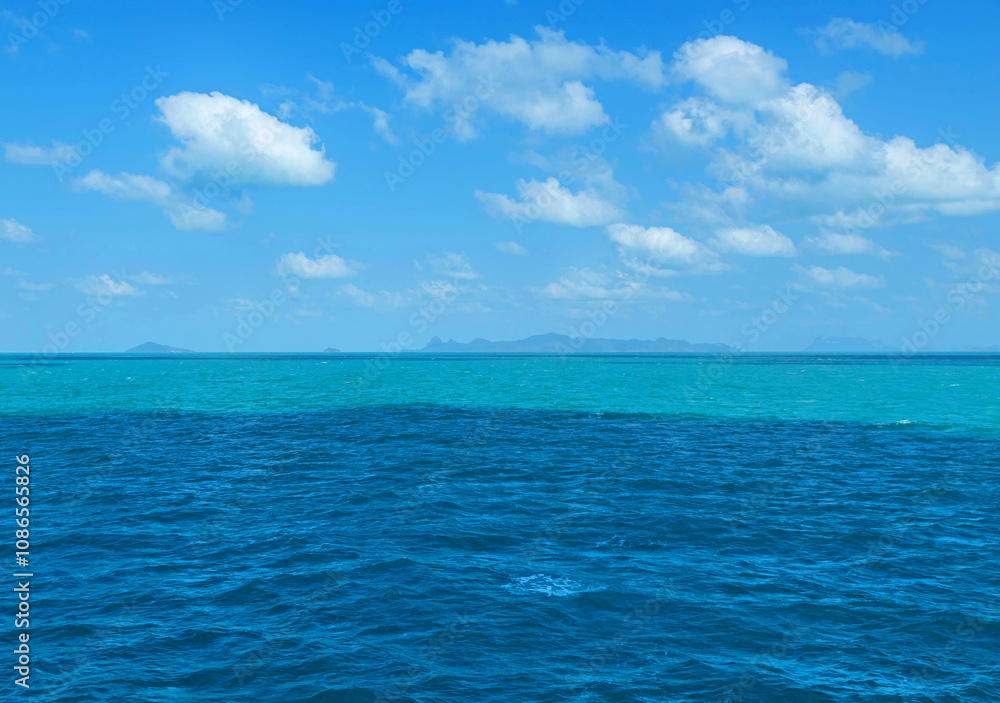 Fototapeta premium Turquoise blue sea ripple with white clouds on clear blue sky in tropical climate 