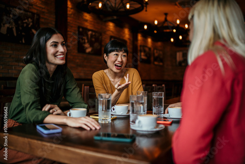 A group of friends catch up over coffee in a cozy cafe, taking a break from their busy lives to spend time together and reconnect photo