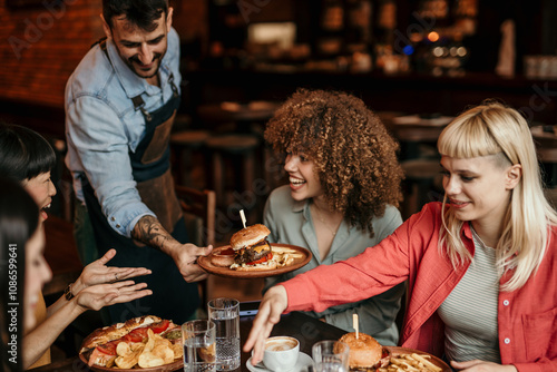 Waiter serving food to a group of multiracial friends