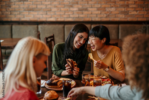Young friends having a great time in restaurant. Multiracial group of young people sitting in a restaurant and smiling.