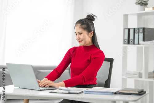 A businesswoman sits at her desk, smiling while talking on the phone and looking at her laptop. She focuses on analyzing tasks, planning strategies, and engaging in productive online discussions.