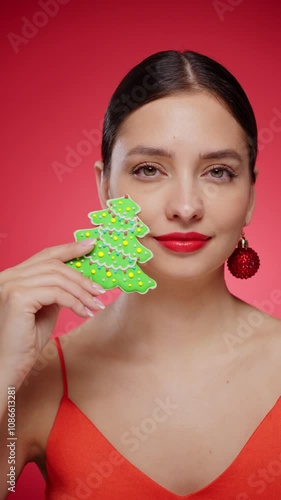 Beautiful young woman with cookie Christmas tree isolated on red background. Christmas or New Year festivities. Holiday and Party. Slow motion vertical video