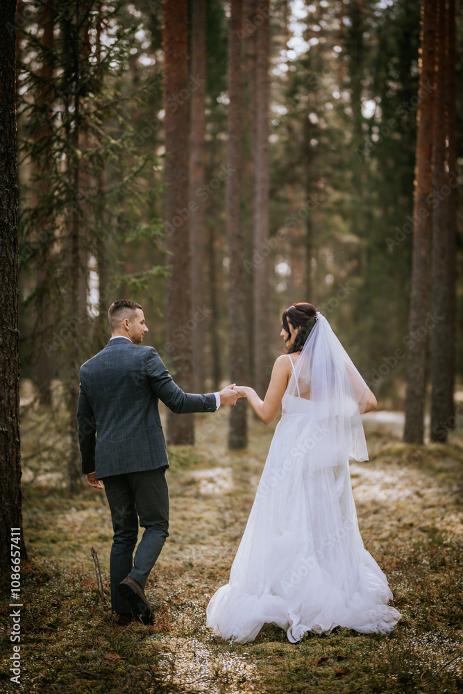 A bride and groom walk hand in hand through a serene forest, with sunlight filtering through tall trees, creating a romantic and peaceful scene.. A bride and groom walk hand in hand through a serene forest, with sunlight filtering through tall trees, creating a romantic and peaceful scene..