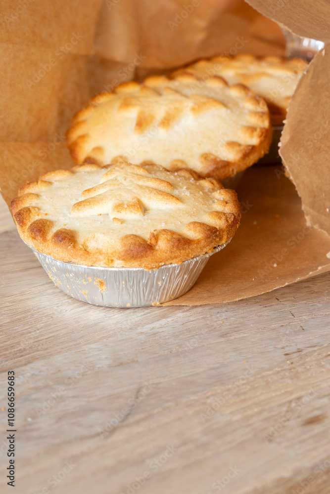 Mince pies in a brown paper bag on a wood chopping board.. Biodegradable recycling environmentally friendly packaging. Mince pies in a brown paper bag on a wood chopping board.. Biodegradable recycling environmentally friendly packaging.
