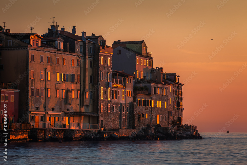 Rovinj, Croatia - View of the beautiful ancient houses and walls of the Old Town of Rovinj on a hot summer afternoon with golden sky at sunset
