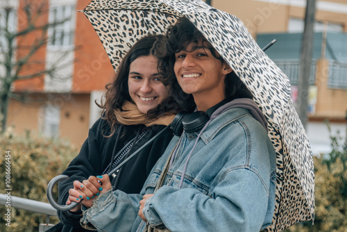 teen couple with umbrella in the rain in the city photo