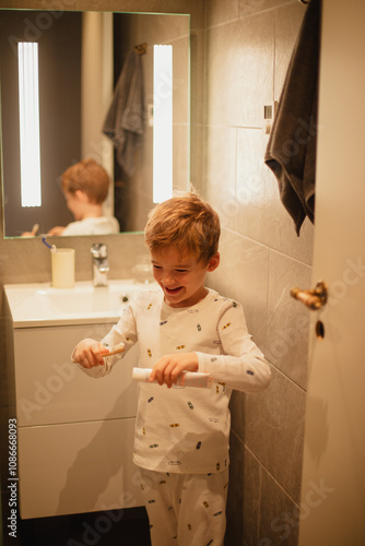 Young boy brushing his teeth independently in a bathroom, practicing good dental hygiene. Ideal for concepts of health, self-care, and children's daily routines. photo