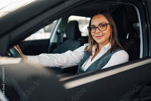 Confident woman smiling in driver's seat of a sleek car.