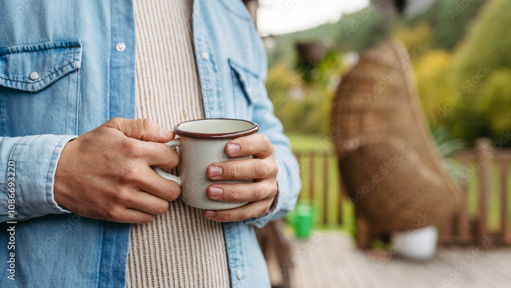 Close up of hands holding cup of warm tea, coffee, having relaxing moment at home, standing on patio autumn nature around. Close up of hands holding cup of warm tea, coffee, having relaxing moment at home, standing on patio autumn nature around.