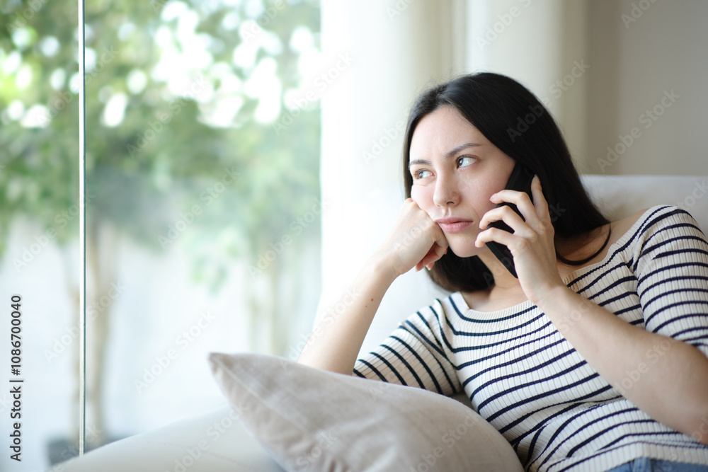 Bored asian woman waiting in a phone conversation at home Bored asian woman waiting in a phone conversation at home