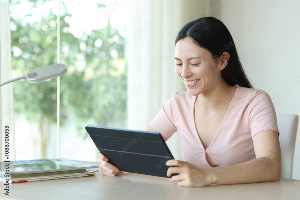 Happy asian woman watching media on tablet at home