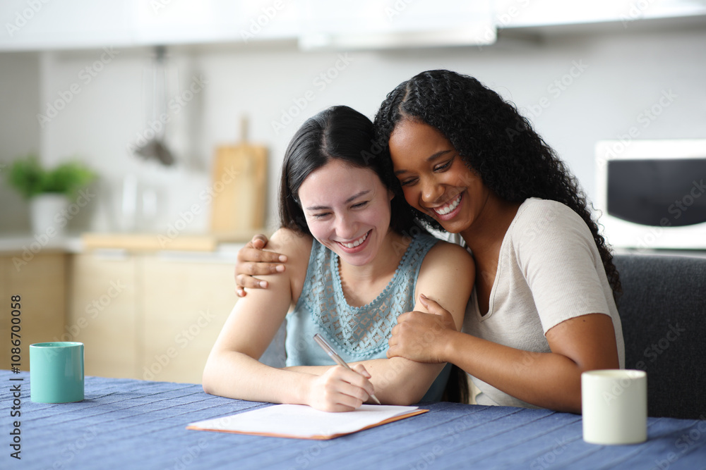 Happy interracial lesbian couple signing contract at home Happy interracial lesbian couple signing contract at home