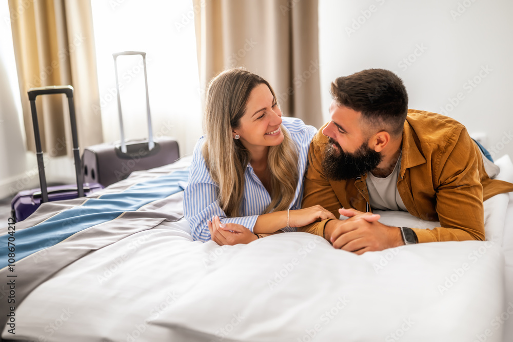 Young happy couple is on vacation. Tourists arrived in hotel room and relaxing on bed. Young happy couple is on vacation. Tourists arrived in hotel room and relaxing on bed.