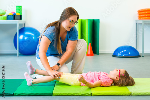 Child with physical disability in physical therapy session. Child living with cerebral palsy exercising with her therapist during physiotherapy. photo