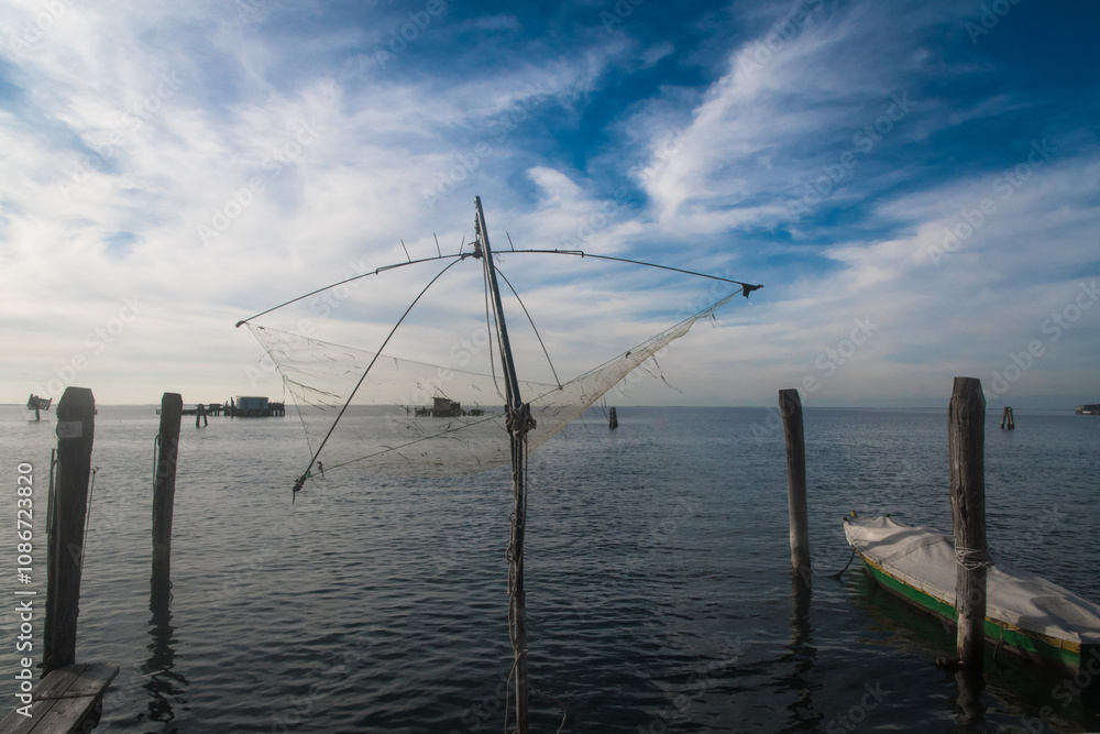 Una rete a bilancia per la pesca sospesa sull’acqua della laguna di Venezia a Pellestrina si staglia contro il cielo azzurro e pieno di belle nuvole in una giornata autunnale Una rete a bilancia per la pesca sospesa sull’acqua della laguna di Venezia a Pellestrina si staglia contro il cielo azzurro e pieno di belle nuvole in una giornata autunnale