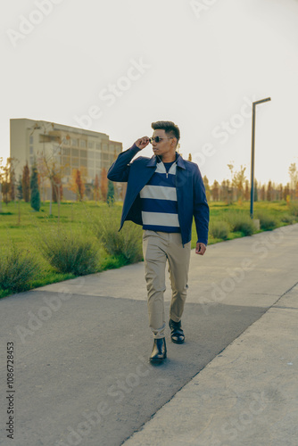 A man wearing a blue and white striped jacket walks down a sidewalk