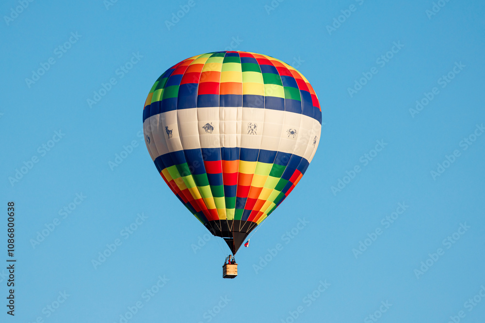 Whispers of Color: A Vibrant Hot Air Balloon Ascends into the Crisp Blue Sky, Painting Dreams Above the World. Whispers of Color: A Vibrant Hot Air Balloon Ascends into the Crisp Blue Sky, Painting Dreams Above the World.