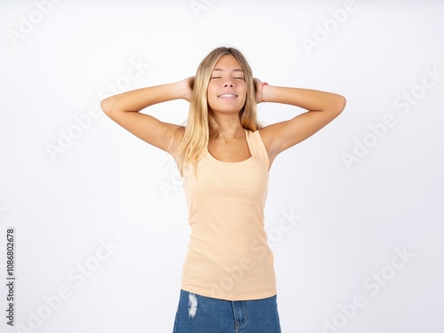 Close up portrait of Beautiful teen girl wearing sleeveless t-shirt who dreams about vacation holding hands behind head