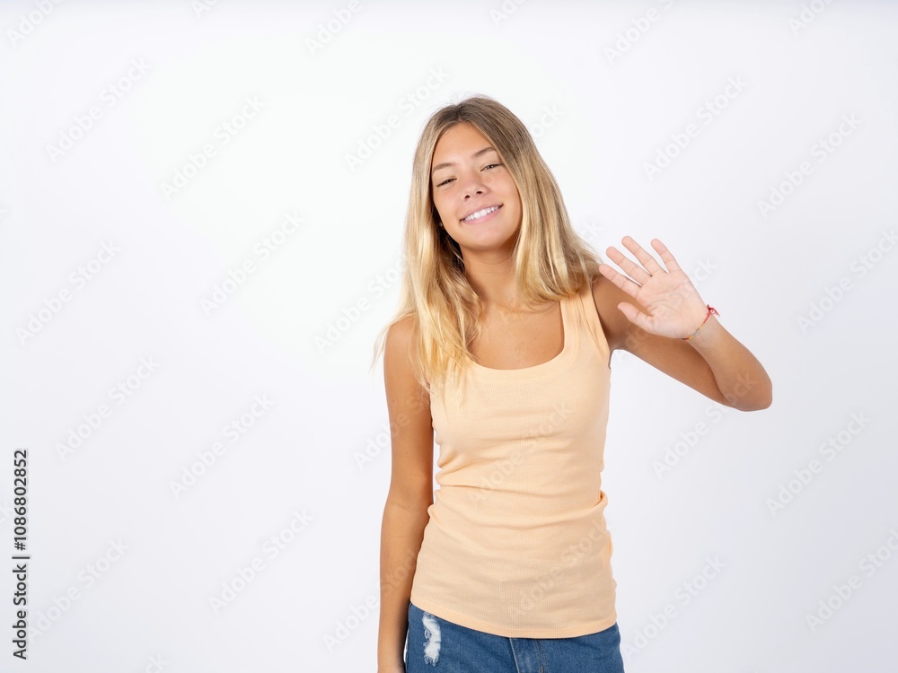 Beautiful teen girl wearing sleeveless t-shirt Waiving saying hello happy and smiling, friendly welcome gesture. Beautiful teen girl wearing sleeveless t-shirt Waiving saying hello happy and smiling, friendly welcome gesture.
