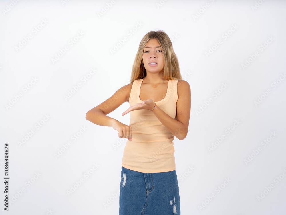 Beautiful teen girl wearing sleeveless t-shirt In hurry pointing to watch time, impatience, upset and angry for deadline delay. Beautiful teen girl wearing sleeveless t-shirt In hurry pointing to watch time, impatience, upset and angry for deadline delay.