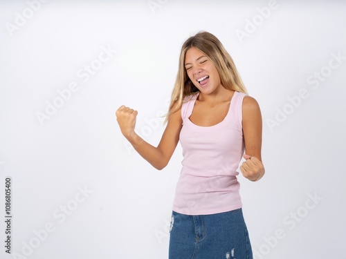 Beautiful teen girl wearing sleeveless t-shirt very happy and excited doing winner gesture with arms raised, smiling and screaming for success. Celebration concept.