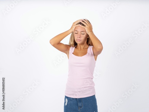 Beautiful teen girl wearing sleeveless t-shirt suffering from strong headache desperate and stressed because of overwork. Depression and pain concept. photo