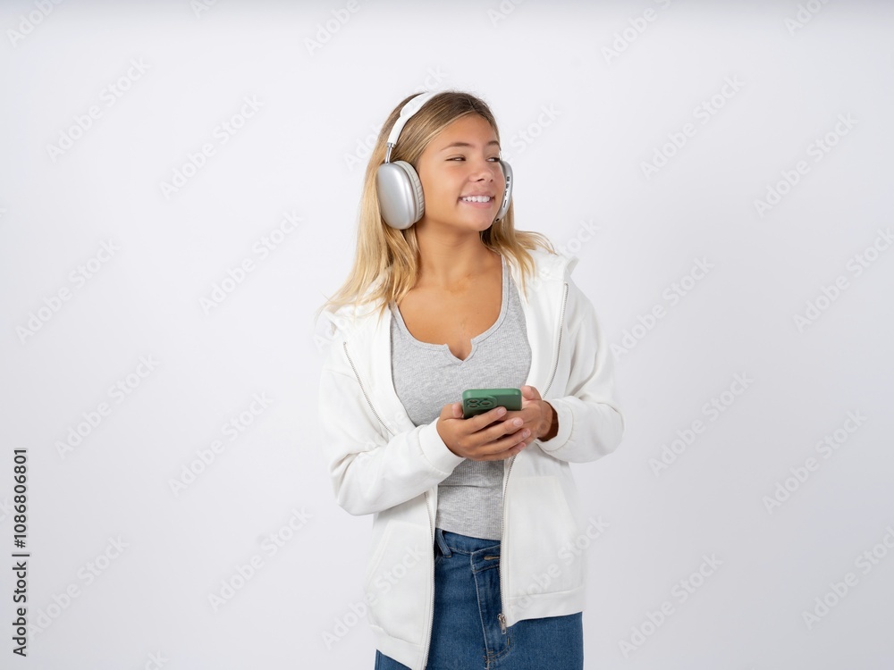 Naklejka premium Beautiful teen girl wearing white jacket hold telephone hands read good youth news look empty space advert