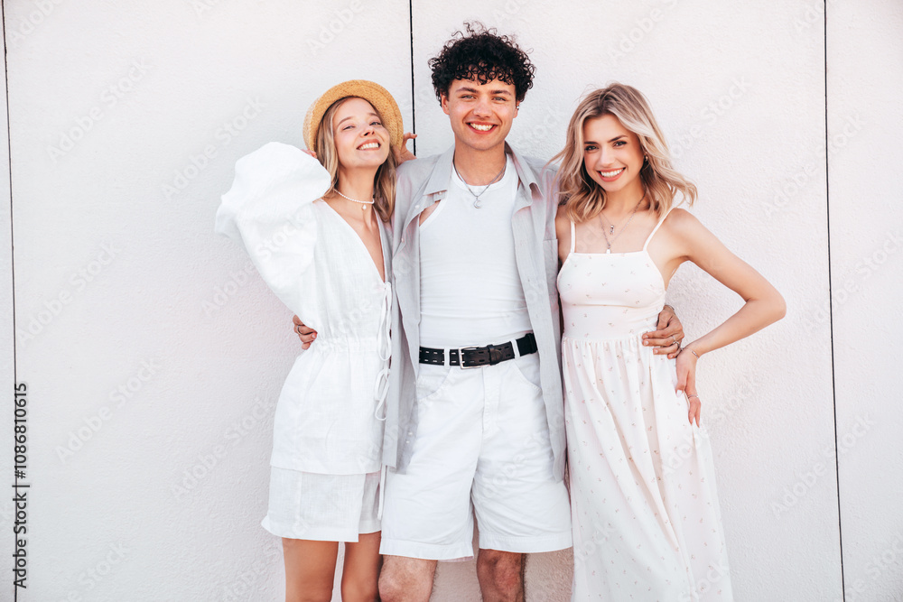 Young three stylish friends posing in the street. Fashion man and two cute female dressed in casual summer clothes. Smiling models having fun. Cheerful women and guy outdoors, in sunny day Young three stylish friends posing in the street. Fashion man and two cute female dressed in casual summer clothes. Smiling models having fun. Cheerful women and guy outdoors, in sunny day