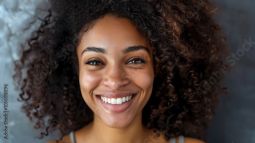 Close-up portrait of a young woman with curly hair smiling at the camera.