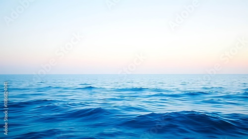 Serene expanse of deep blue ocean water with gentle waves rippling under a soft, pastel sky