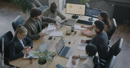 Team leader talking to diverse group of people employees giving documents leading meeting in office. Professional cooperation and businesspeople concept.