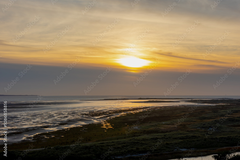 Landscape view of dunes in evening with golden sunlight during the sunset, Marshland and sand dike on the Dutch Wadden Sea island Terschelling, A municipality and an island in Friesland, Netherlands. Landscape view of dunes in evening with golden sunlight during the sunset, Marshland and sand dike on the Dutch Wadden Sea island Terschelling, A municipality and an island in Friesland, Netherlands.