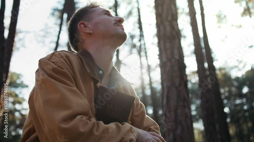 Christian read and pray with holy bible in forest with Holy light shining. Pray to God to confess your sins and ask for blessings to overcome his problems. faith, and religion.