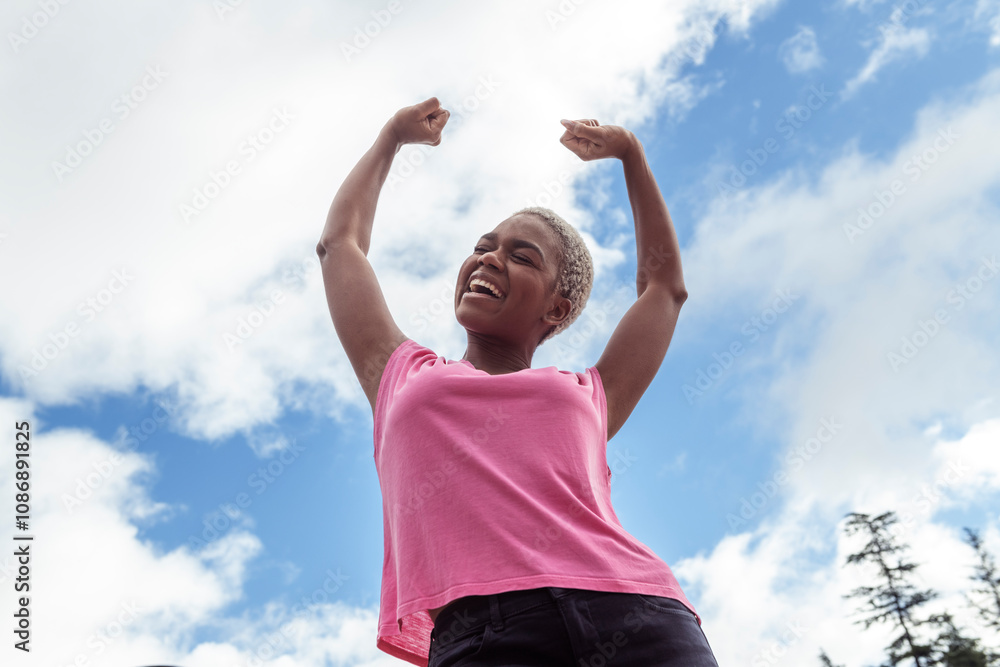 Cheerful young woman standing with arms raised under cloudy sky Cheerful young woman standing with arms raised under cloudy sky