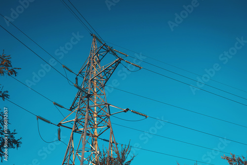 a high-voltage power transmission line, in the photo, a power line support against a blue sky. Posts with wires of high voltage on background of blue sky in sunlight.  Group of power lines. photo