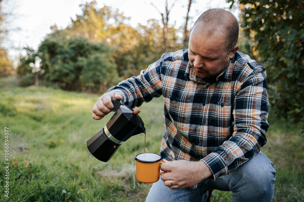 Man pouring coffee in cup on grass at sunset Man pouring coffee in cup on grass at sunset