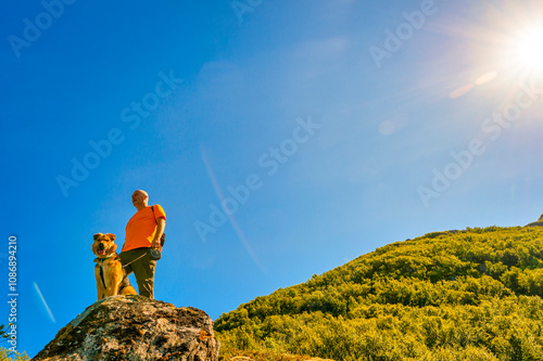 Adventurous man with dog looking at view from lofoten islands photo