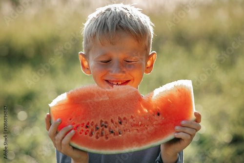 Happy boy having slice of watermelon on sunny day photo