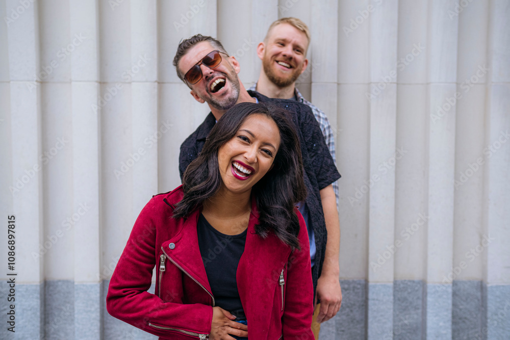 Happy woman with friends standing in front of wall on sunny day Happy woman with friends standing in front of wall on sunny day
