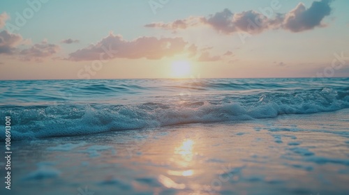 Summer sunset over calm ocean waves highlighting vibrant colors in the sky and soft reflections on sandy shores with gentle clouds scattered above.