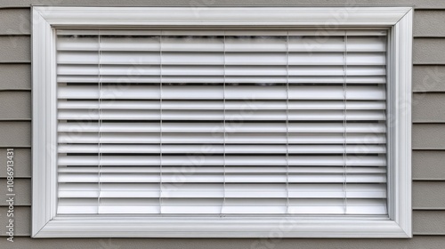 White blinds in a framed window against a textured wall, creating a clean and modern look with evenly spaced slats for light control.