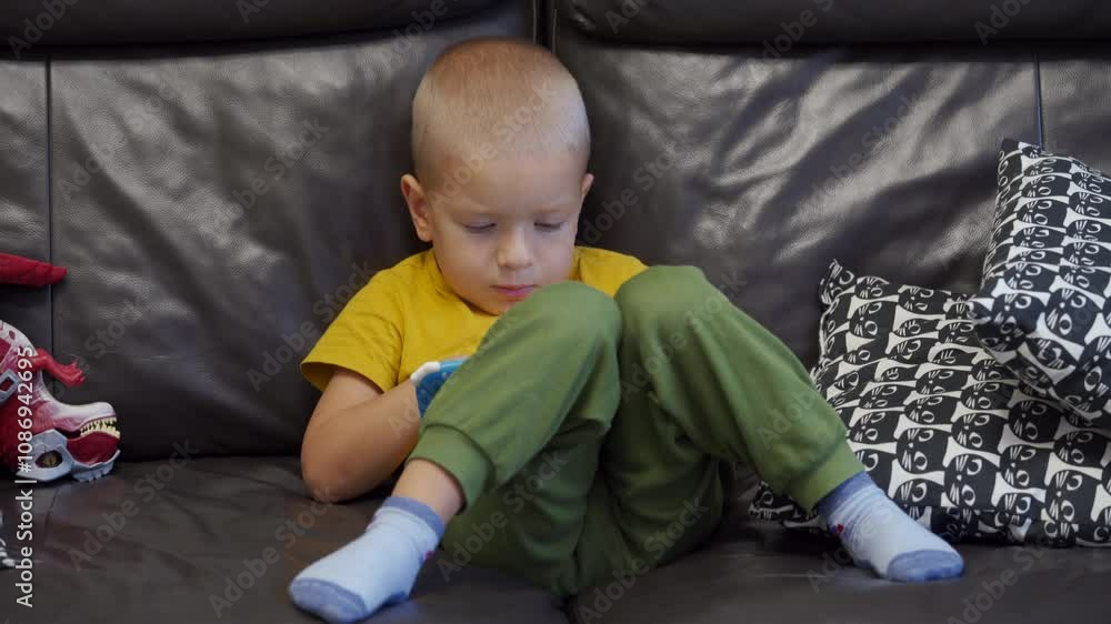 Child sitting on sofa and playing on tablet for kids. Little boy's face smiling while playing. Child sitting on sofa and playing on tablet for kids. Little boy's face smiling while playing.