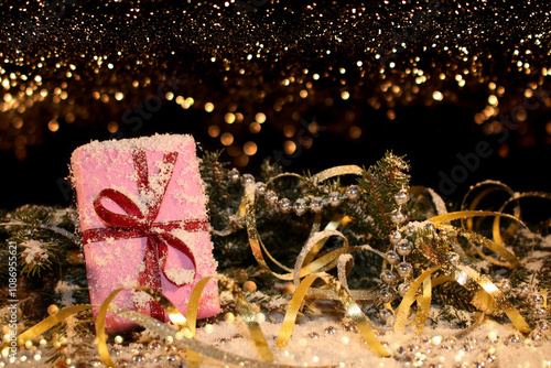 Christmas background with a pink gift on the background of a snow-covered green fir tree on a shiny background