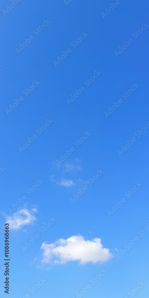 Fototapeta premium Clear blue sky with a few fluffy white clouds on a sunny day, scenic, bright